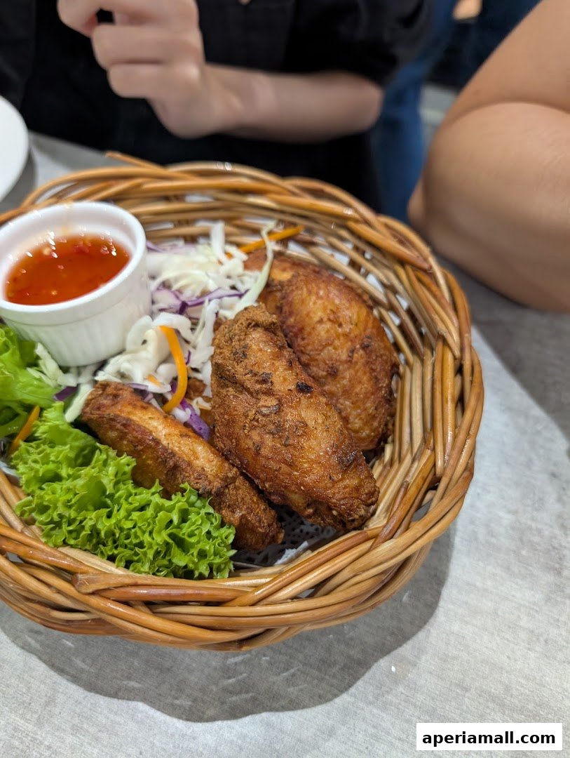 Crispy fried chicken wings served in a woven basket with dipping sauce and salad.