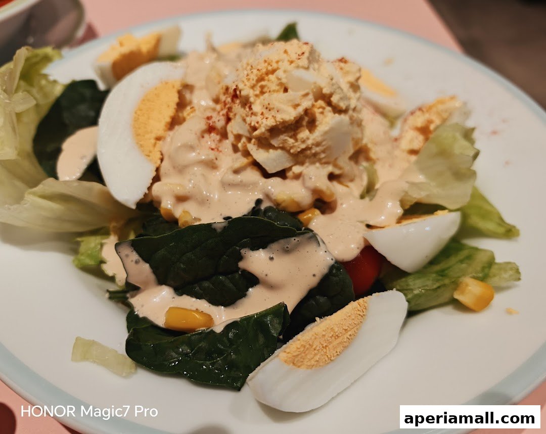 A close-up of a salad with lettuce, spinach, corn, tomatoes, hard-boiled eggs, and dressing.