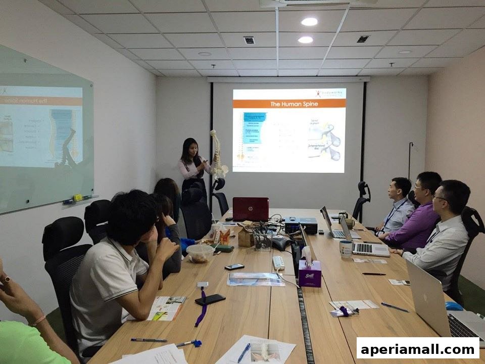 A presenter explains the human spine to an audience in a modern conference room.