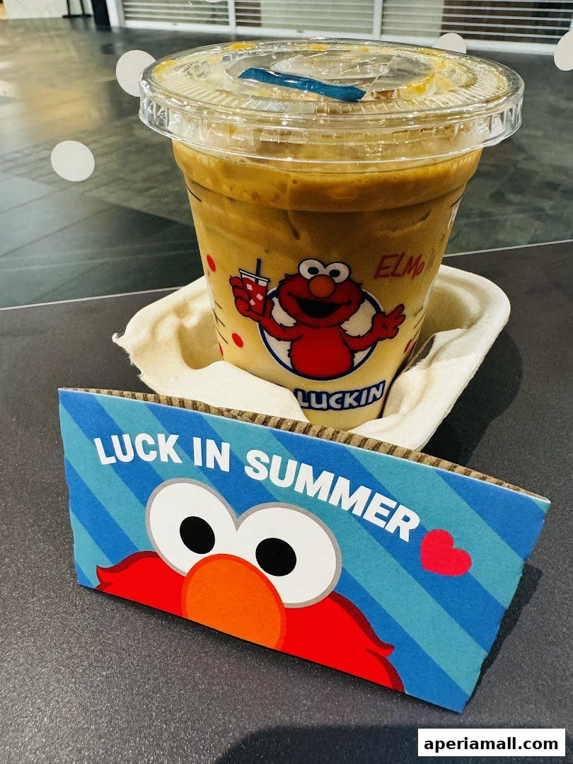 A cold coffee drink with Elmo branding and a 'Luck in Summer' sleeve.