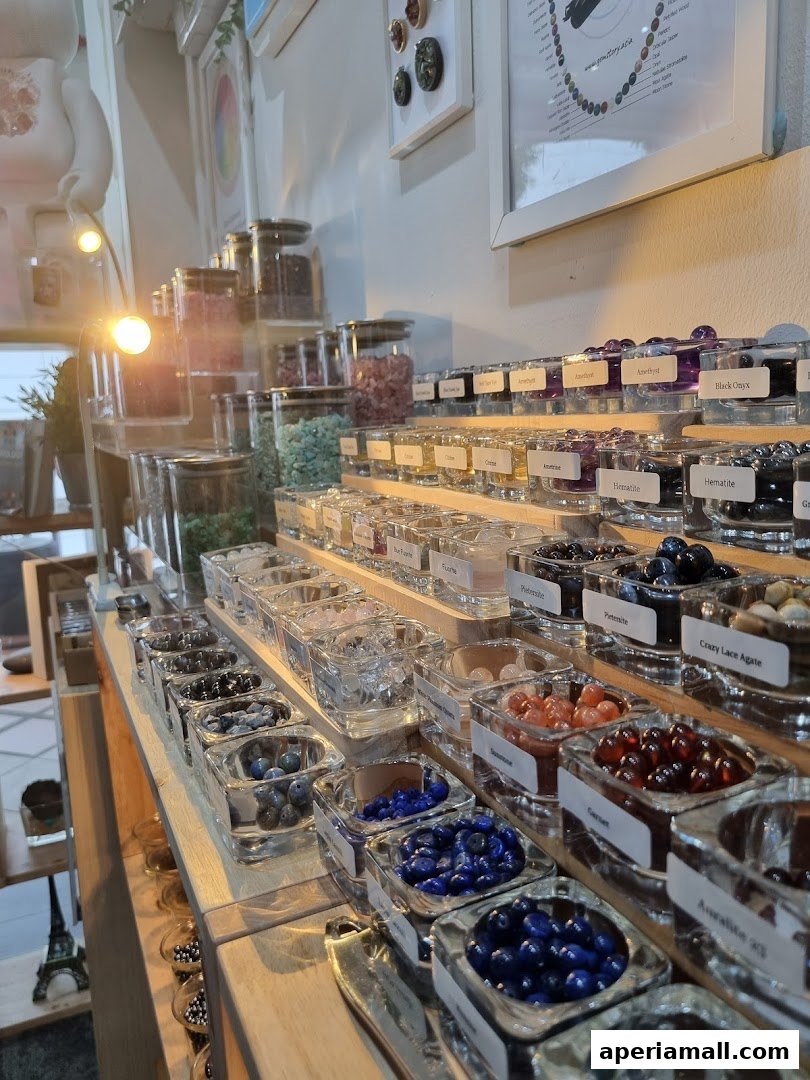 A display of various colorful gemstones and beads in clear glass containers.