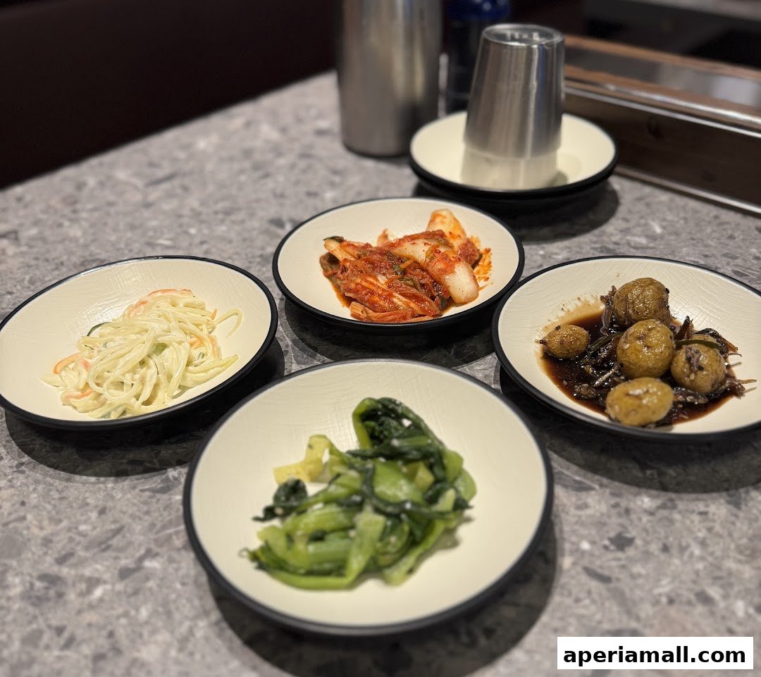 A close-up of four small bowls of Korean side dishes, including kimchi and vegetables.