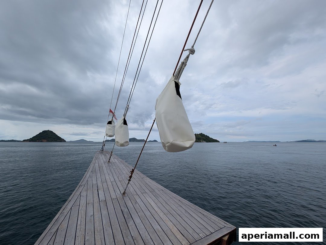 View from a wooden deck of a boat looking out at islands under a cloudy sky.