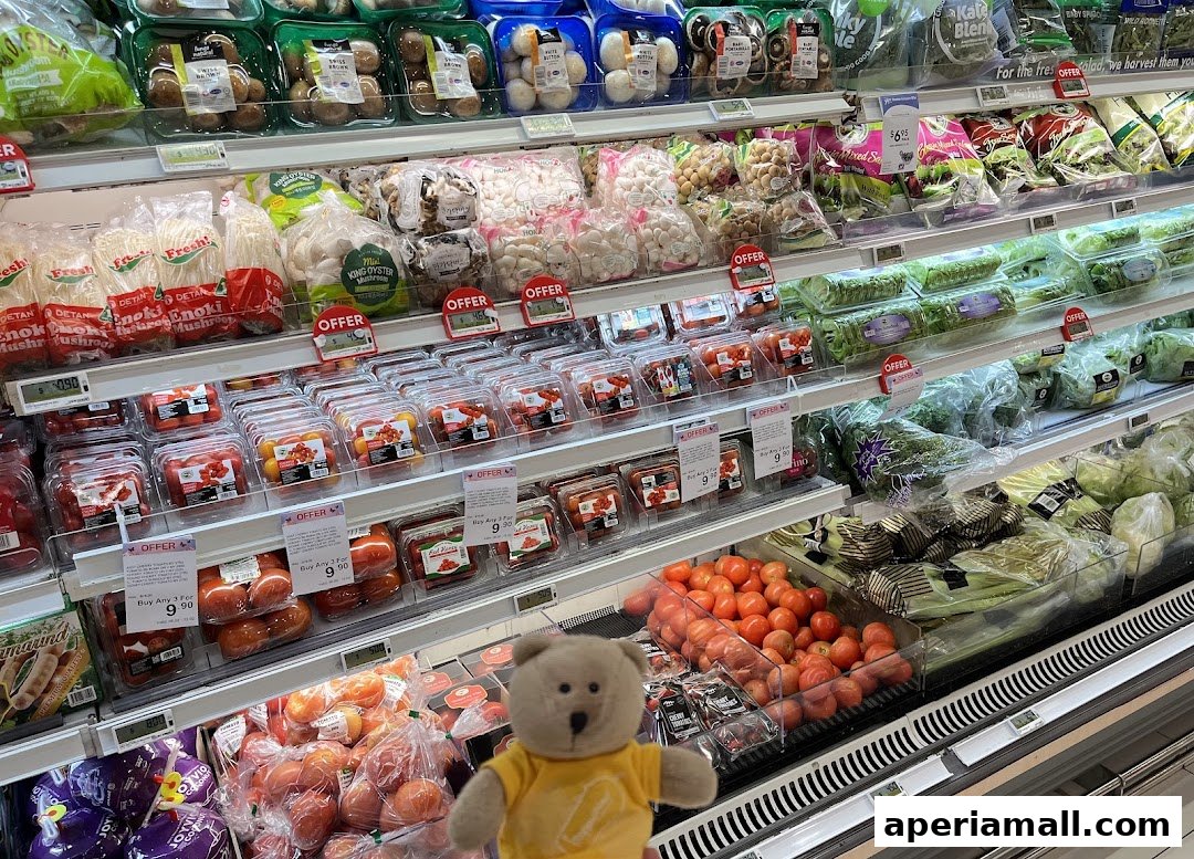 A display of fresh produce, including mushrooms, tomatoes, and leafy greens, with a teddy bear in the foreground.