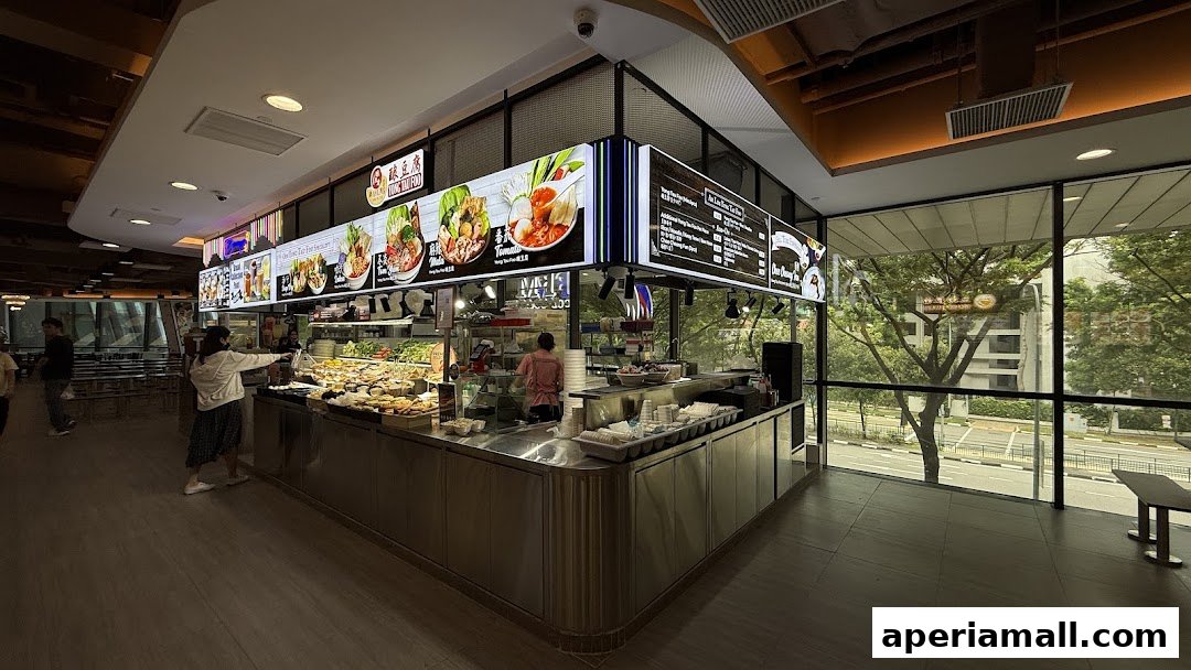 A food stall with illuminated menu boards and a display of food items.