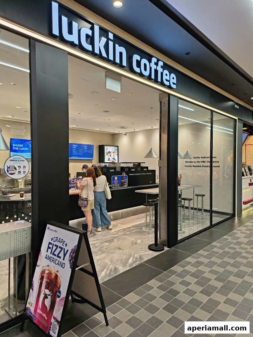 The entrance of a Luckin Coffee shop with a promotional sign for Grape Fizzy Americano.
