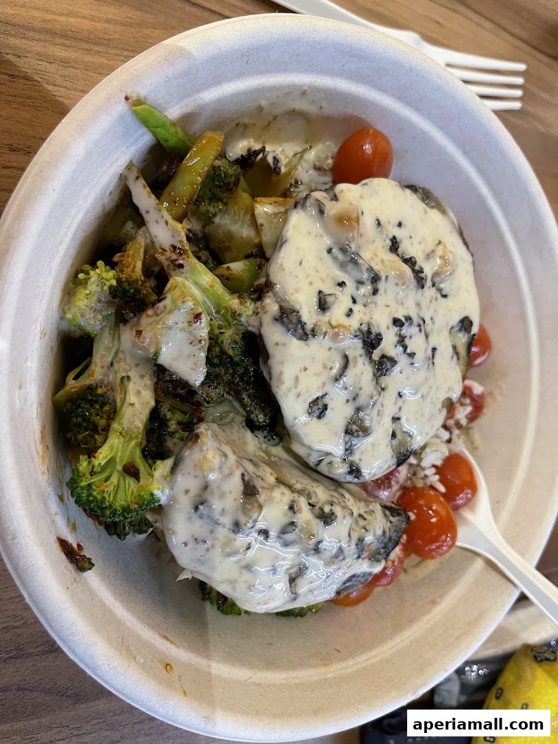 A healthy salad bowl with broccoli, asparagus, cherry tomatoes, and a creamy sauce.