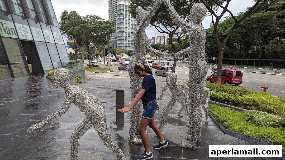 A young girl interacts with wireframe sculptures outside a modern building with a street view.