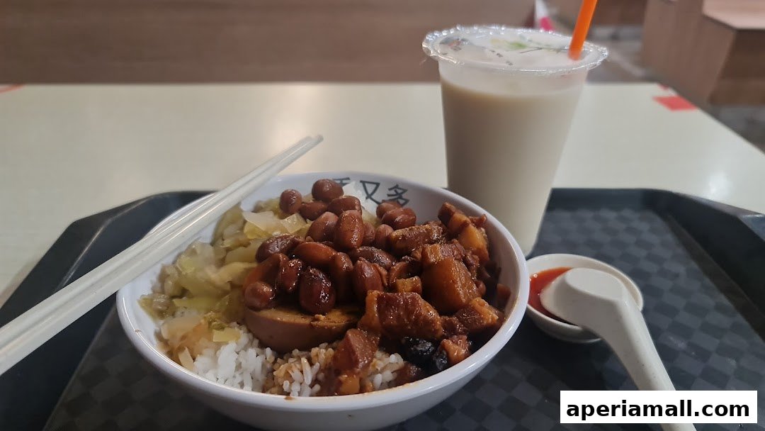 A bowl of rice with braised pork, peanuts, and pickled cabbage, served with a drink.