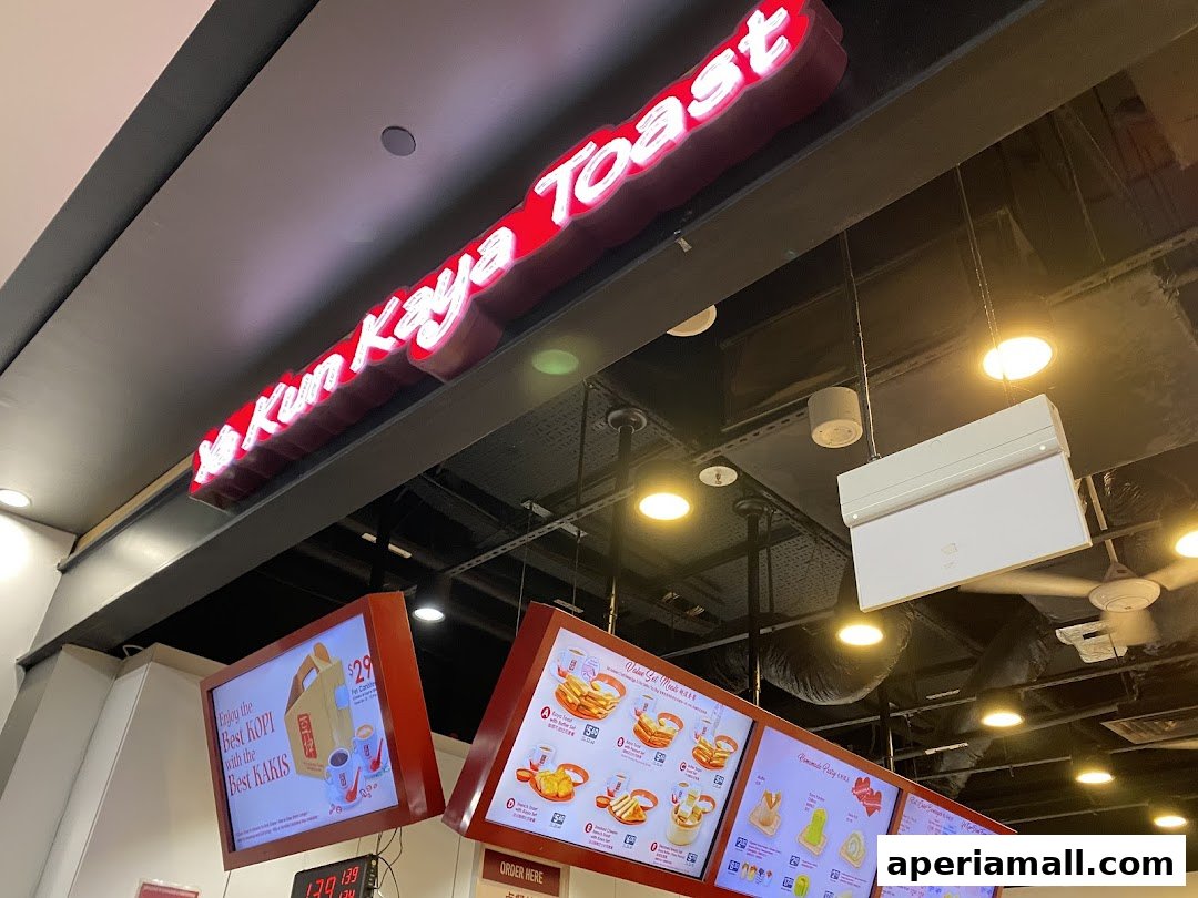 A bright sign for Ya Kun Kaya Toast with digital menus displaying food items.