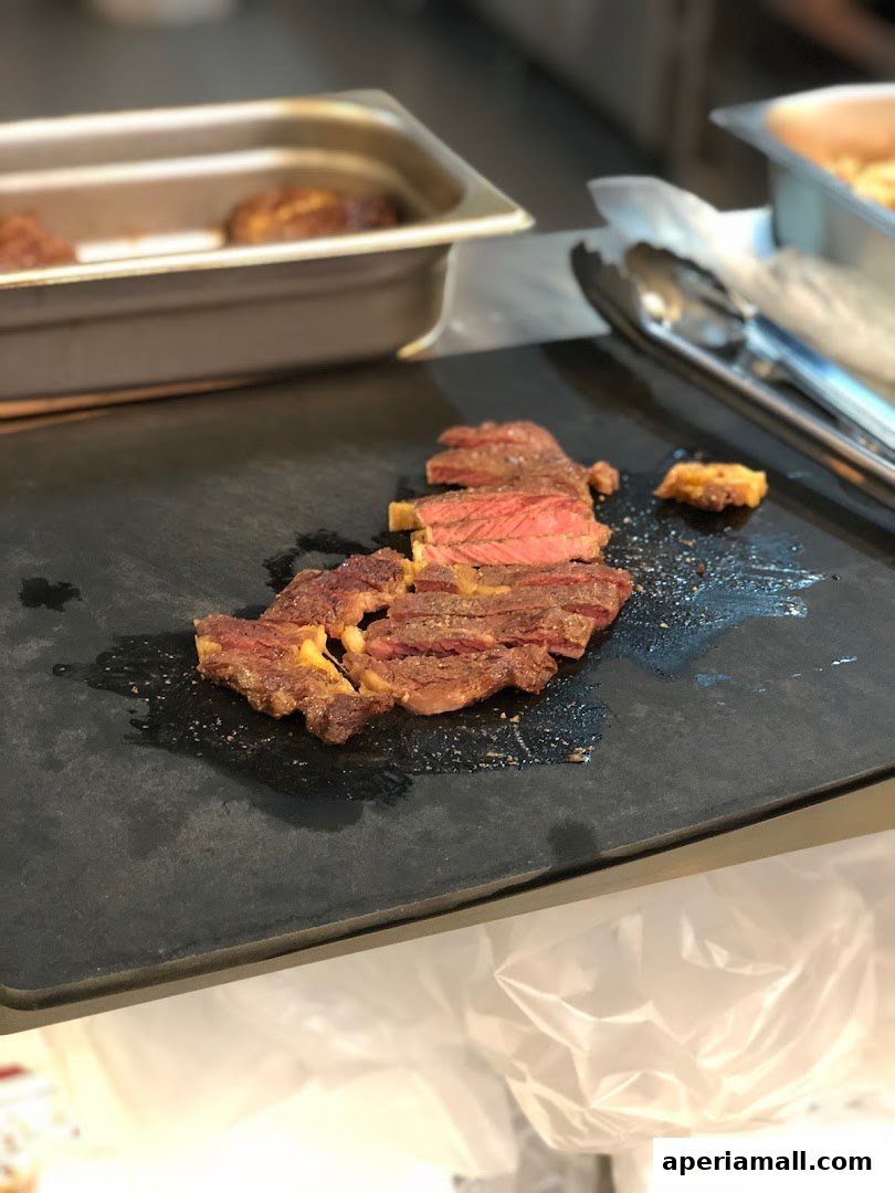 Sliced steak seasoned with salt and pepper on a black cutting board.