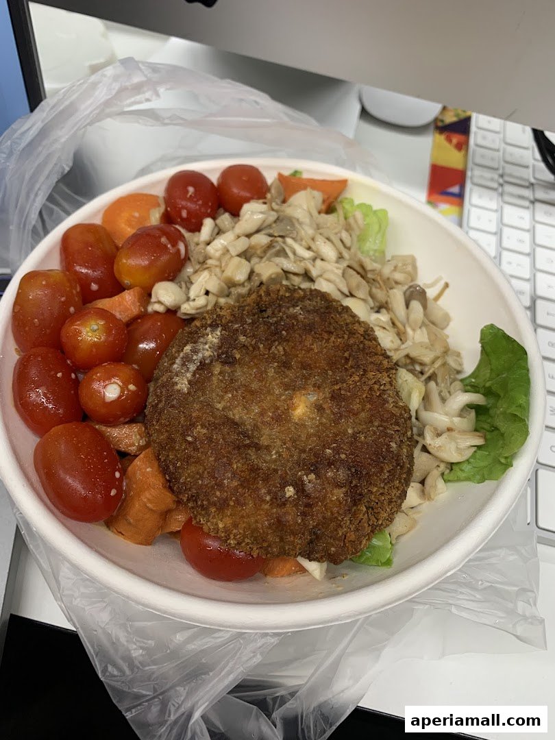 A healthy salad bowl with a crispy patty, cherry tomatoes, carrots, and mushrooms.