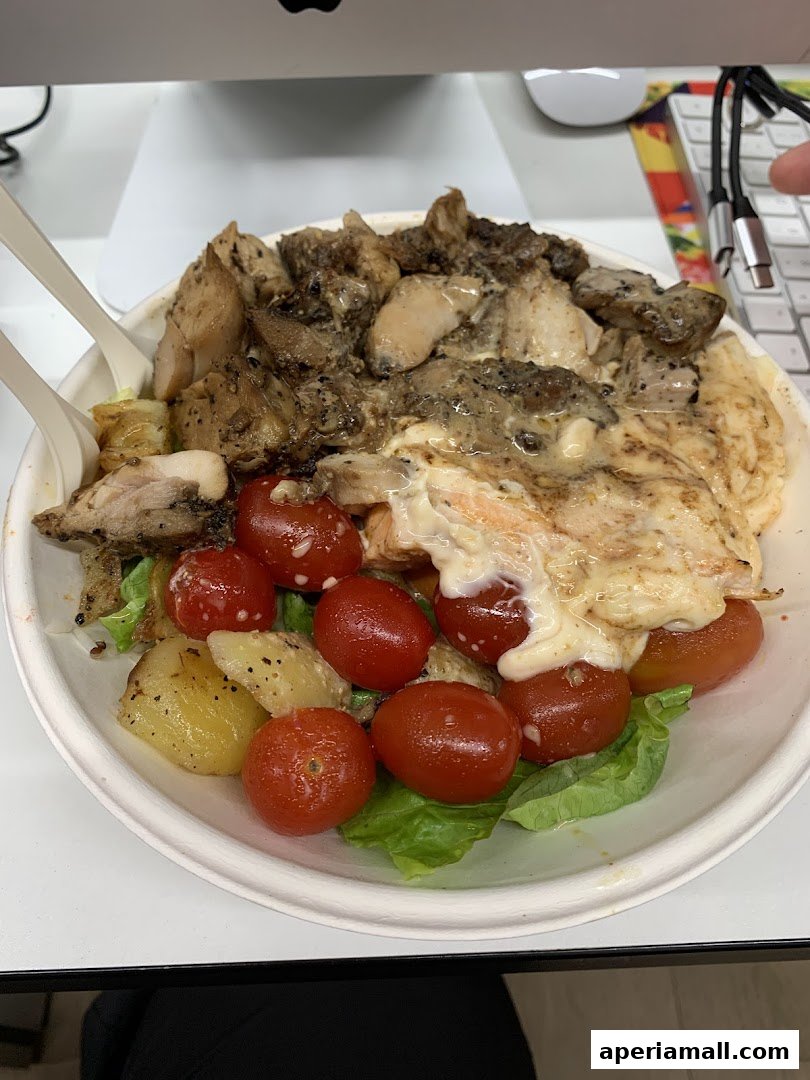 A healthy salad bowl with grilled chicken, salmon, cherry tomatoes, and potatoes.