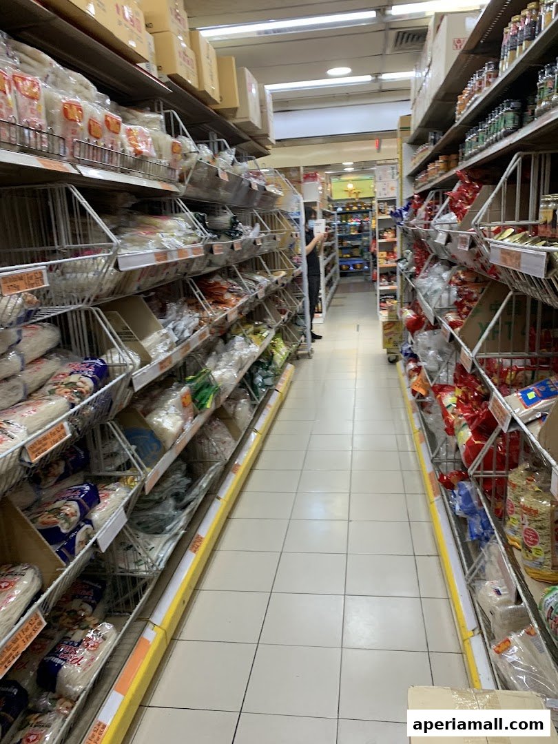 Aisle of a supermarket with shelves stocked with various food products and ingredients.