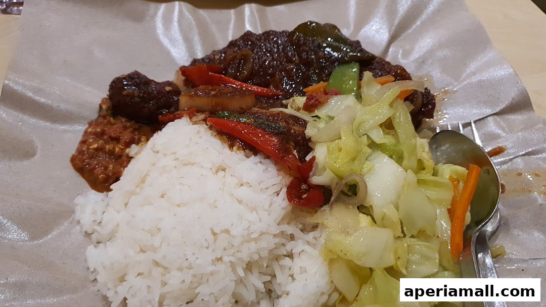 A plate of rice with stir-fried vegetables, chili, and meat, served on brown paper.