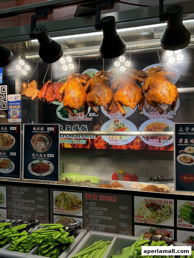 A display of roasted chickens and various noodle and rice dishes at a food stall.