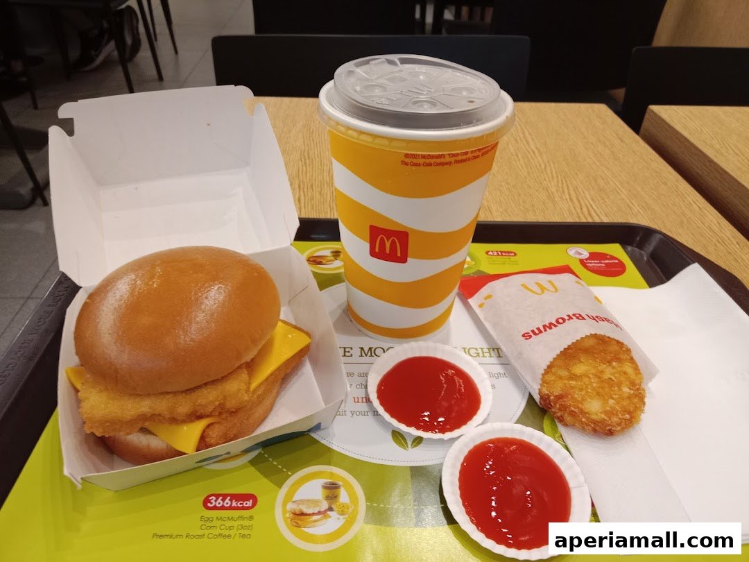 A McDonald's meal featuring an Egg McMuffin, hash browns, a drink, and ketchup.