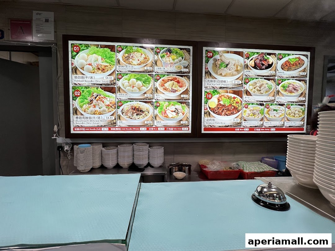 A digital menu board displaying various noodle dishes and other food items with prices.