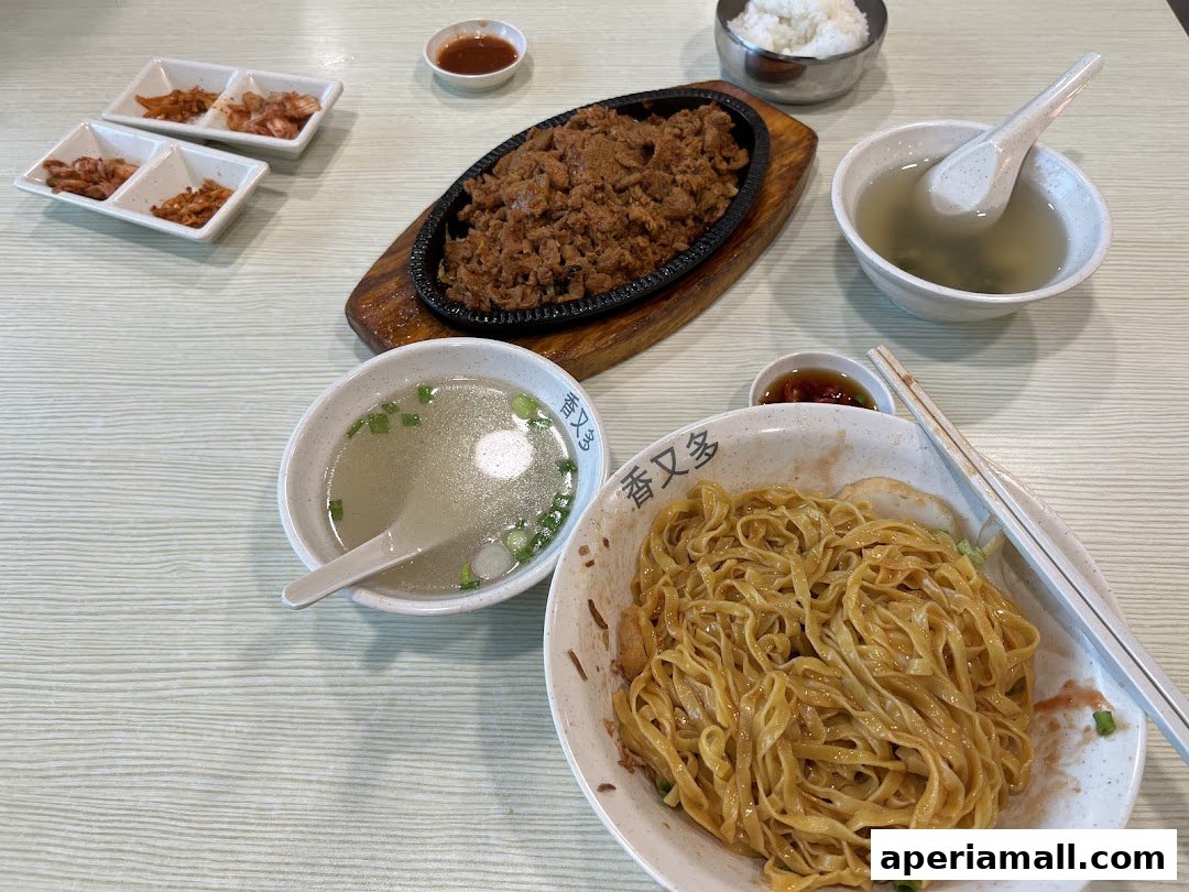 A table setting with a bowl of noodles, soup, rice, and side dishes.