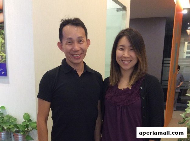 A male and female chiropractor smiling at the camera in a clinic setting.