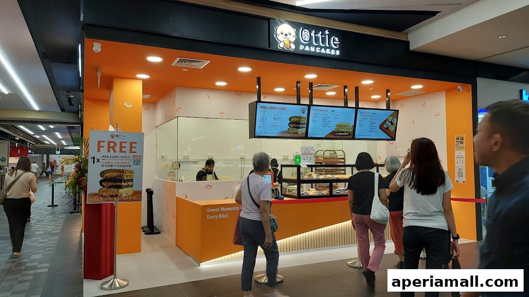 A bright orange and white Ottie Pancakes shop with customers queuing.