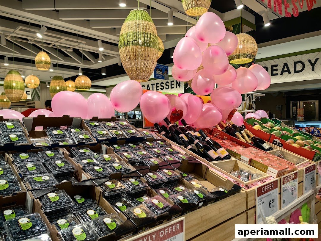 A display of fresh blueberries, wine bottles, and fruits, decorated with pink balloons.
