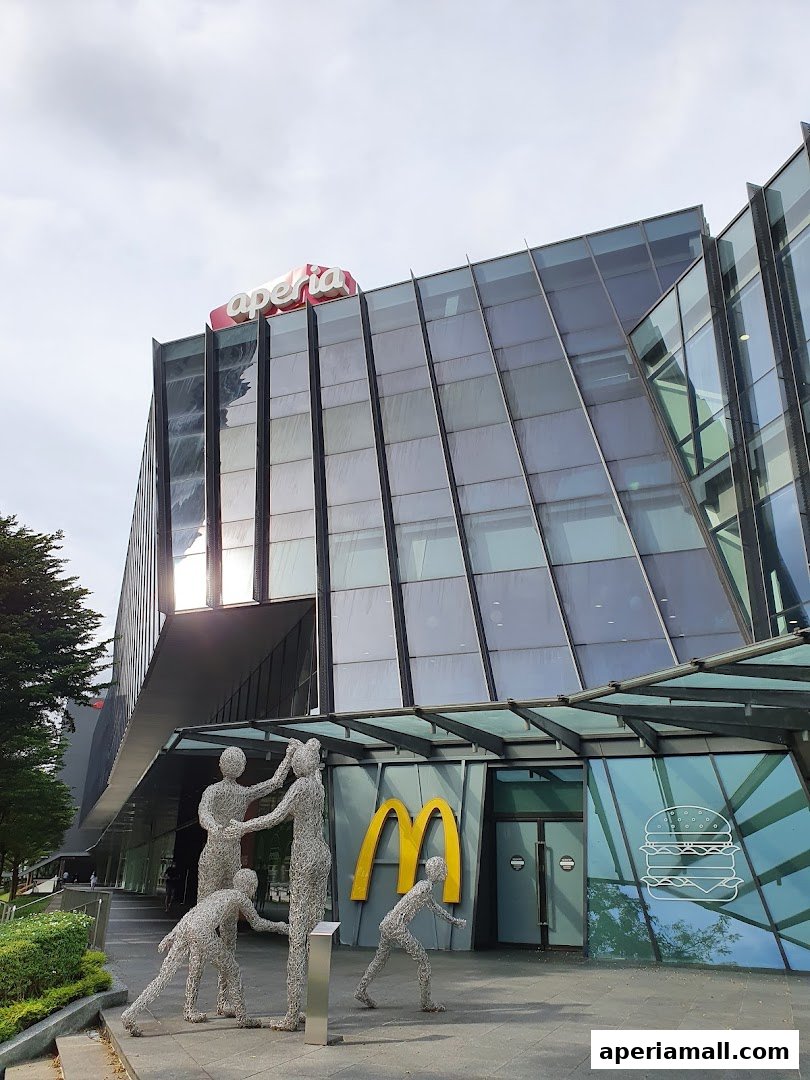 Exterior of a modern building with a McDonald's entrance and abstract sculptures.