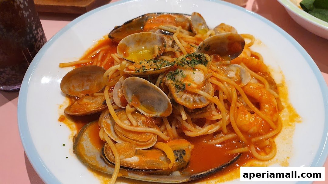 A plate of spaghetti with seafood in a tomato-based sauce, garnished with herbs.