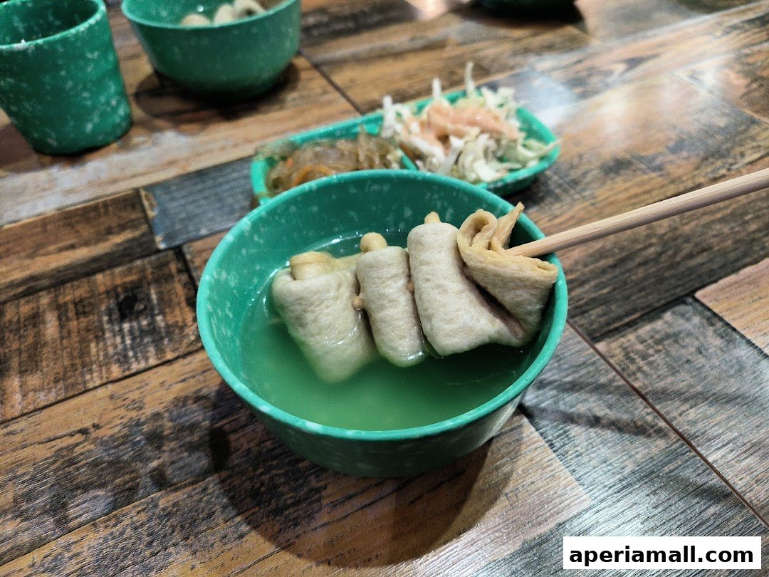 A close-up of fish cakes in broth, served with side dishes on a wooden table.
