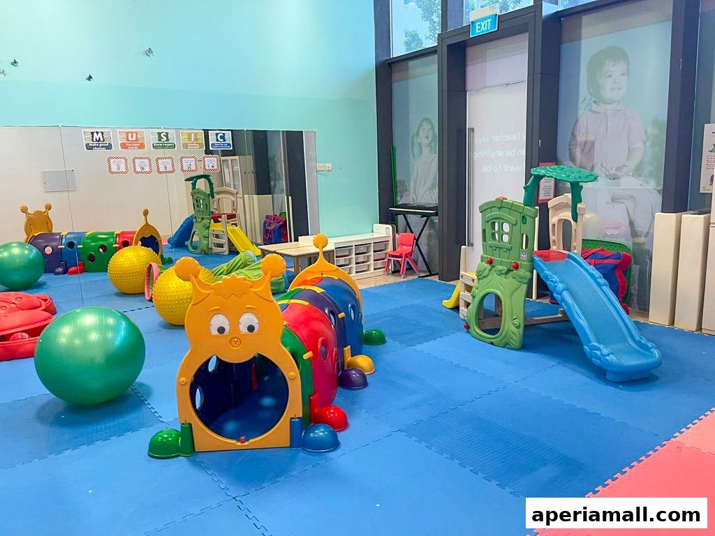 A colorful indoor play area for children with soft mats, slides, and a caterpillar tunnel.