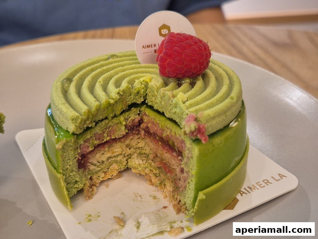 A sliced green matcha cake with raspberry topping on a white plate.