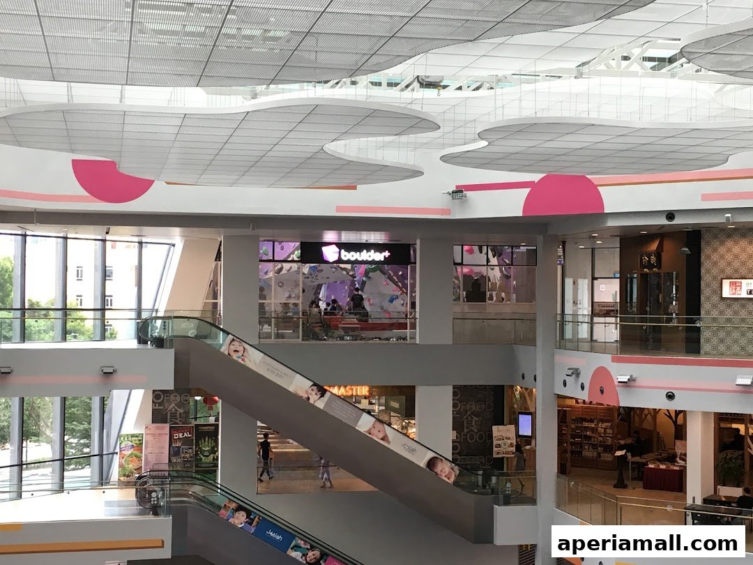 Interior view of a shopping mall with escalators and various shops, including a climbing gym.