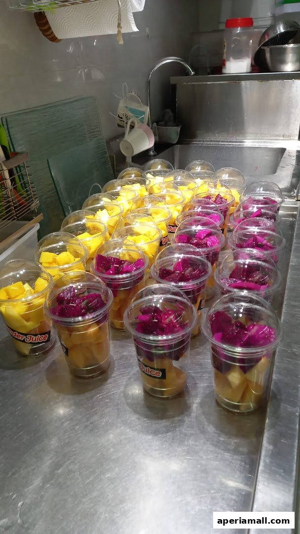 Rows of clear cups filled with fresh cut mango and dragon fruit, ready for sale.