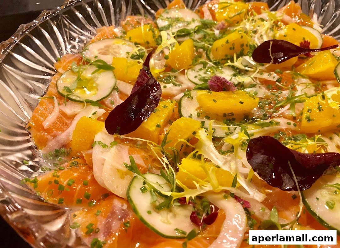 A close-up of a refreshing salmon salad with oranges, cucumbers, and edible flowers.
