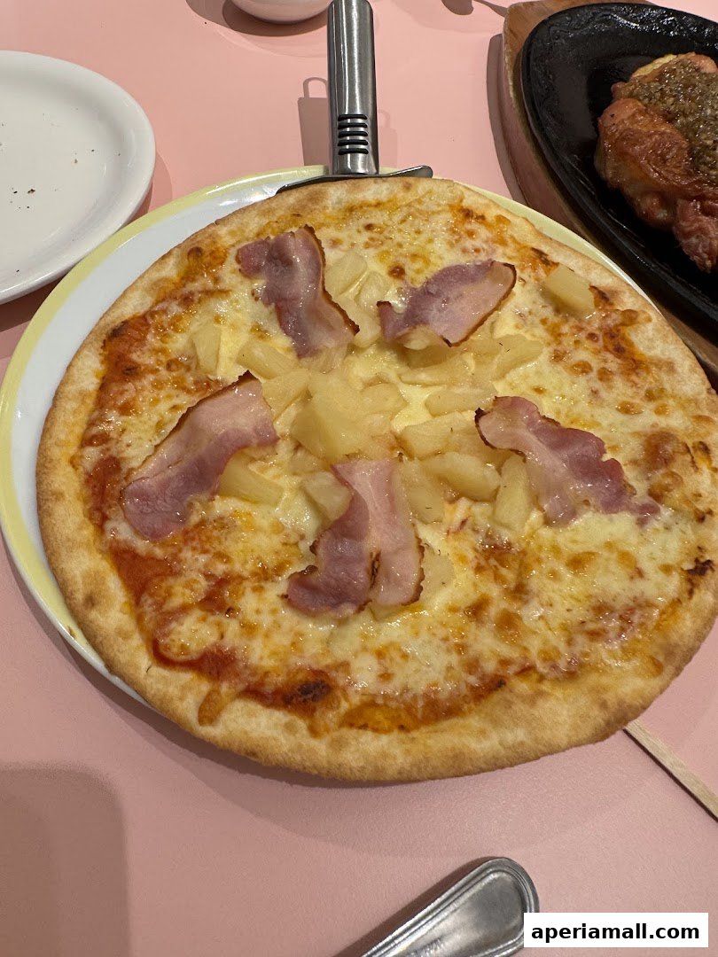 A delicious pizza with pineapple and bacon, served with a pizza cutter.