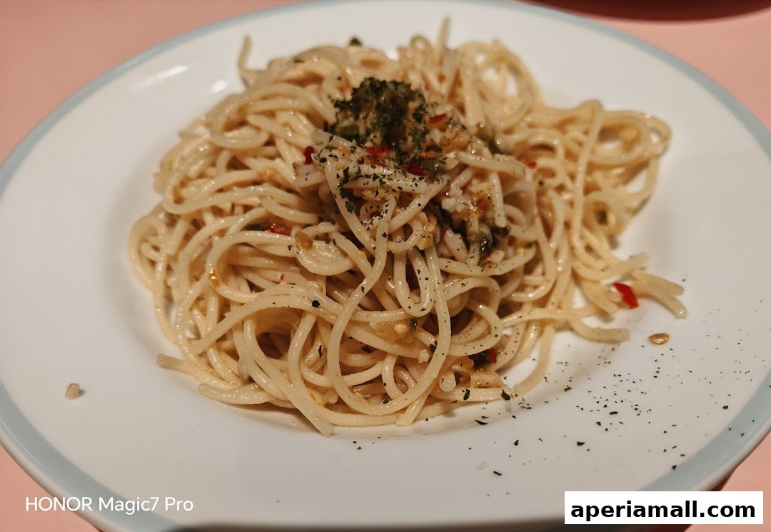 A plate of spaghetti aglio e olio with herbs and chili flakes.