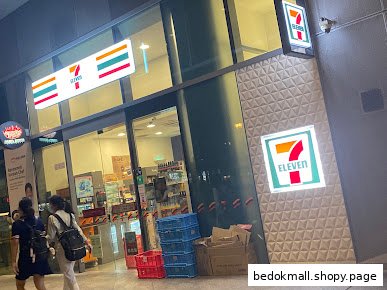 7-Eleven shop front with glass entrance and illuminated logos at night.
