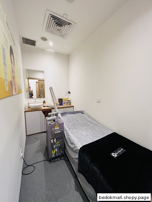 An aesthetic treatment room with a bed, sink, and equipment.
