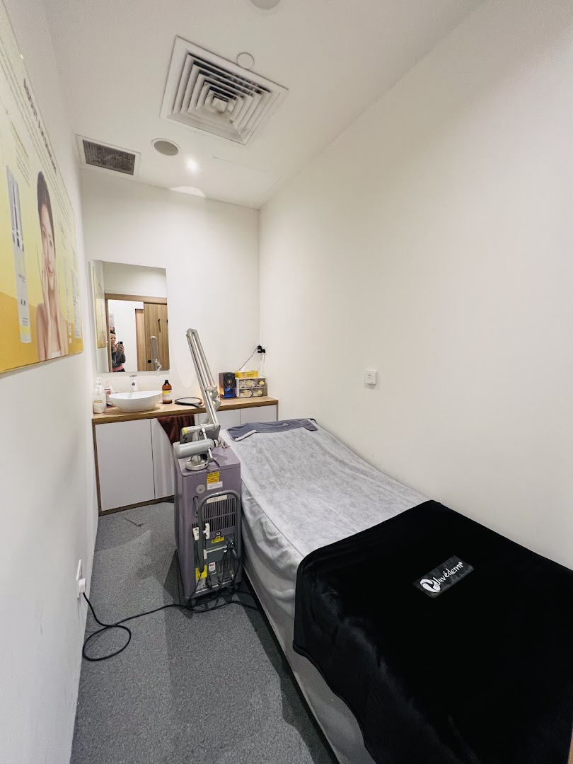 An aesthetic treatment room with a bed, sink, and specialized equipment.