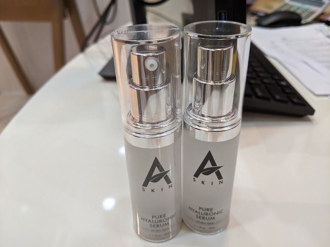 Two bottles of A Skin Pure Hyaluronic Serum on a white desk.