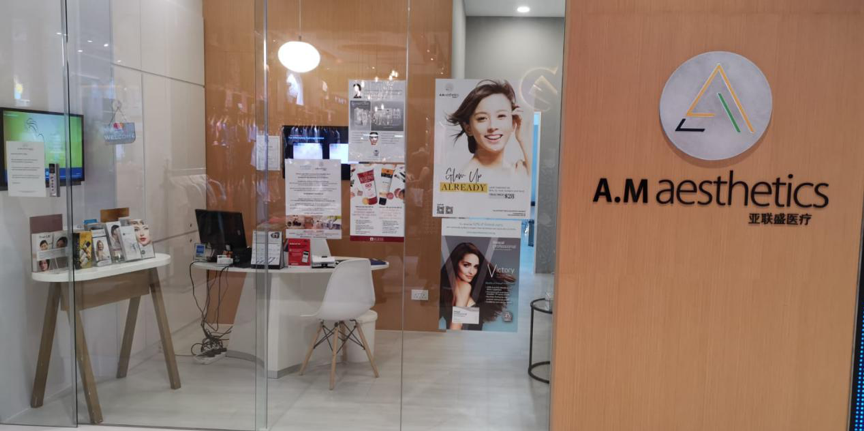 Glass shop front of A.M Aesthetics with reception desk and posters inside.
