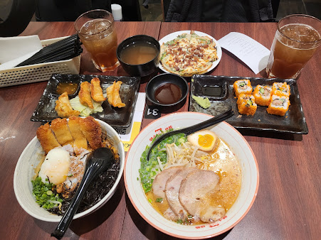 Table full of various Japanese dishes including ramen, gyoza, and sushi.
