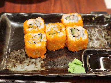 Sushi rolls with roe and wasabi on a dark plate.