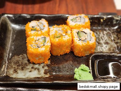 Sushi rolls with roe and wasabi on a dark plate.