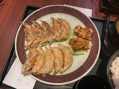 A plate of gyoza and fried chicken with rice and soup.
