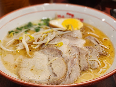 Close-up of a bowl of ramen with pork, bean sprouts, and an egg.
