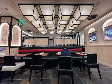 Restaurant interior with booth seating, tables, and unique ceiling lights.
