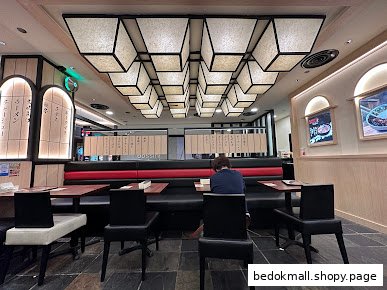 Restaurant interior with booth seating, tables, and unique ceiling lights.