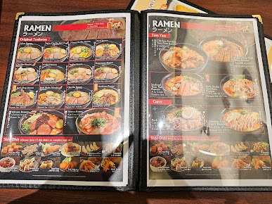 An open menu displaying various ramen and side dishes with prices.