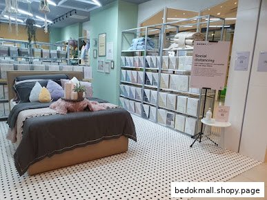 Interior view of a bedding shop with a display bed and product shelves.